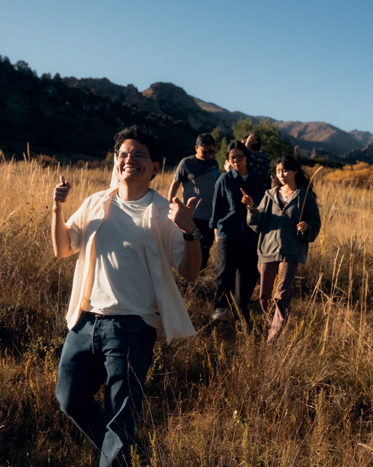 Students walking together through a golden field toward the mountains, the invitation to join YWAM Château