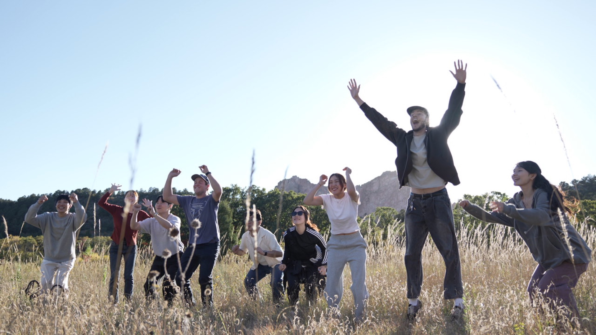 SPL students jumping together in a field, celebrating community